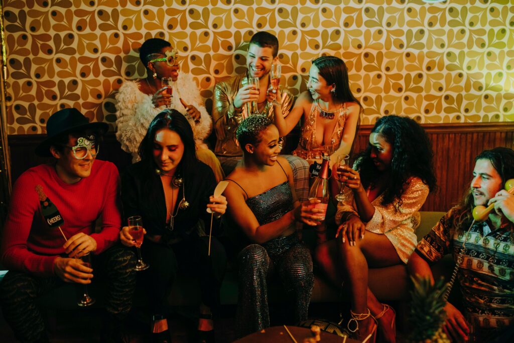A joyful group of diverse friends celebrating at a holiday party with drinks and festive decorations.