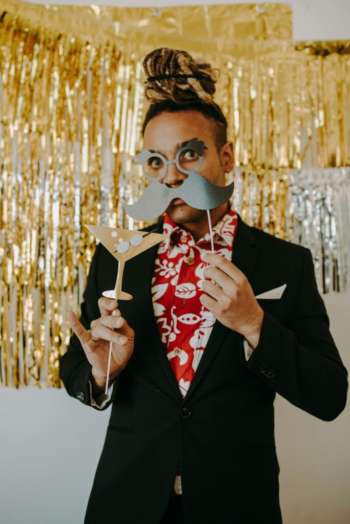 A cheerful adult in festive attire with fun props at a party setting, perfect for holiday celebrations.
