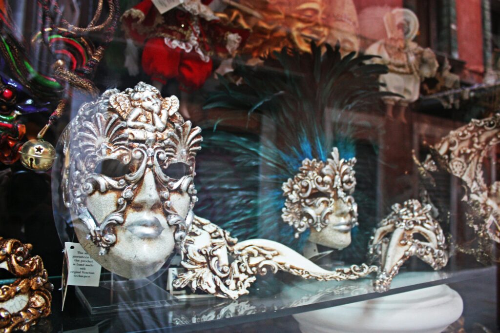 Discover the elegance of traditional Venetian masks in a vibrant shop window. Perfect for Masquerade lovers.